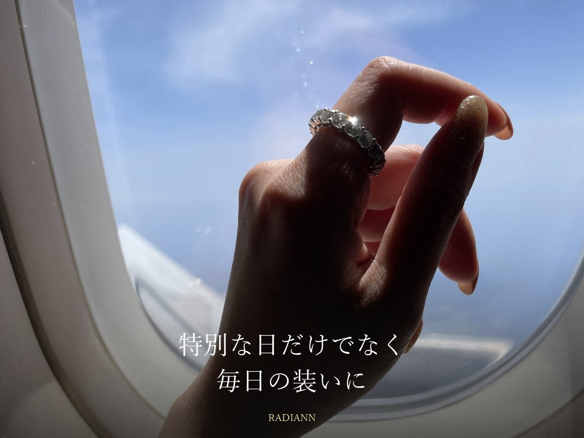 飛行機の窓辺で大粒のモアサナイトリングを着けた手元